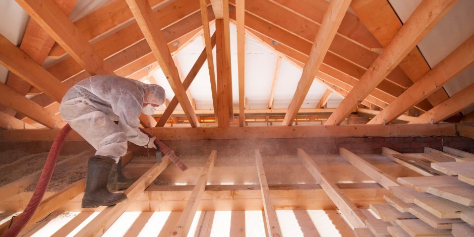 worker using hose blowing spray foam insulation in attic